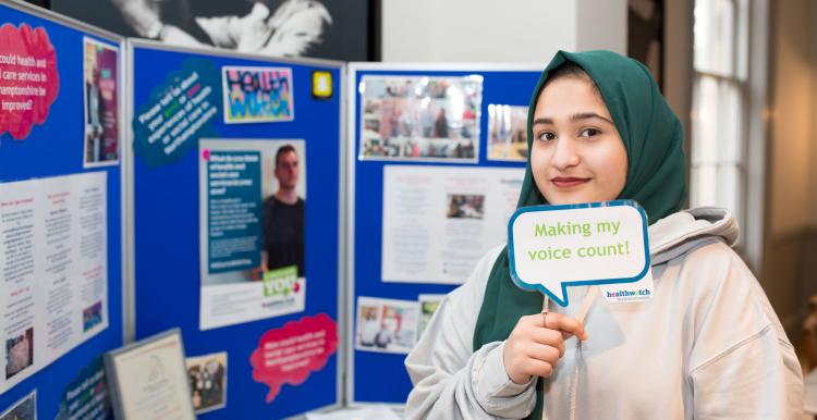 Young girl standing in front of a Healthwatch notice board