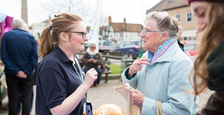 Young Healthwatch volunteer speaking outside to an elderly woman