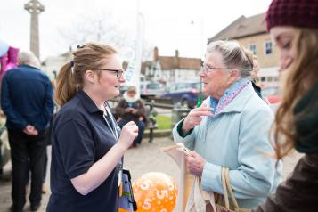 Young Healthwatch volunteer speaking outside to an elderly woman