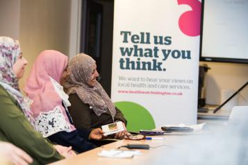 Three women sitting in front of a banner "Tell us what you think"