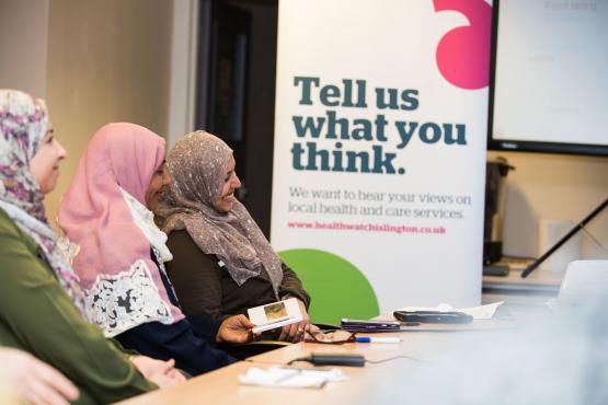 Three women sitting in front of a banner "Tell us what you think"