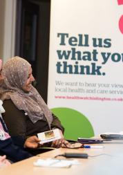 Three women sitting in front of a banner "Tell us what you think"